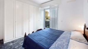 Ein Schlafzimmer mit Bett, Deckenventilator und Blick ins Freie.