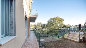 Ein Gebäude mit einem Balkon, einem gepflasterten Weg und einer Treppe, die zu einer höheren Ebene führt.