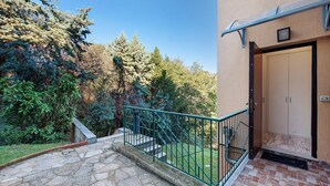 Una entrada de edificio con una escalera de piedra, barandilla de metal y una puerta.