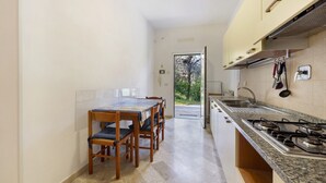 Une cuisine étroite avec une table et des chaises, un fourneau et un évier.