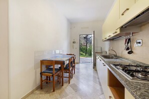 Een koelkast, een kookplaat, een waterkoker, kookgerei, borden en bestek