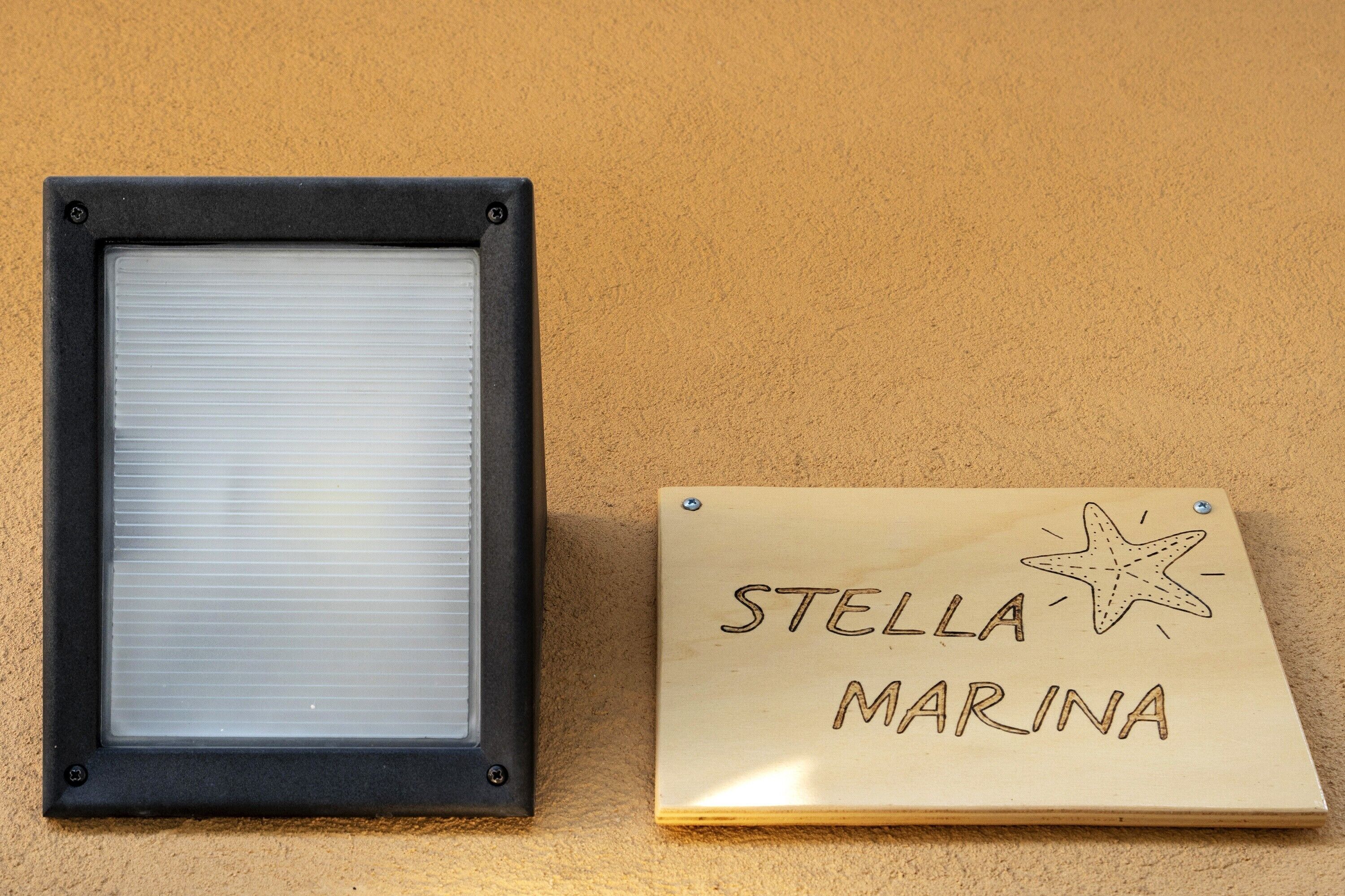 Ein gerahmtes Fenster und ein Holzschild mit der Aufschrift 'STELLA MARINA'.