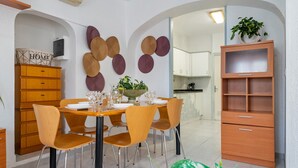 Un comedor con una mesa redonda, sillas, un aparador y una pared decorada con platos.