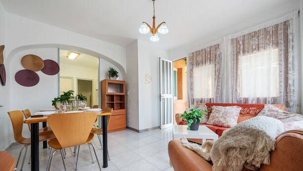 Una sala de estar moderna con comedor, un sofá y una araña.