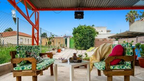 Un patio al aire libre con mobiliario de madera, una mesa y plantas en macetas.