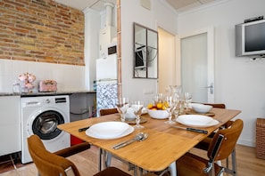 A kitchen with a washing machine, dining table set with plates, glasses, and cutlery. - Vacation Home "Delta Home" with Private Terrace & Wi-Fi (DELTEBRE)