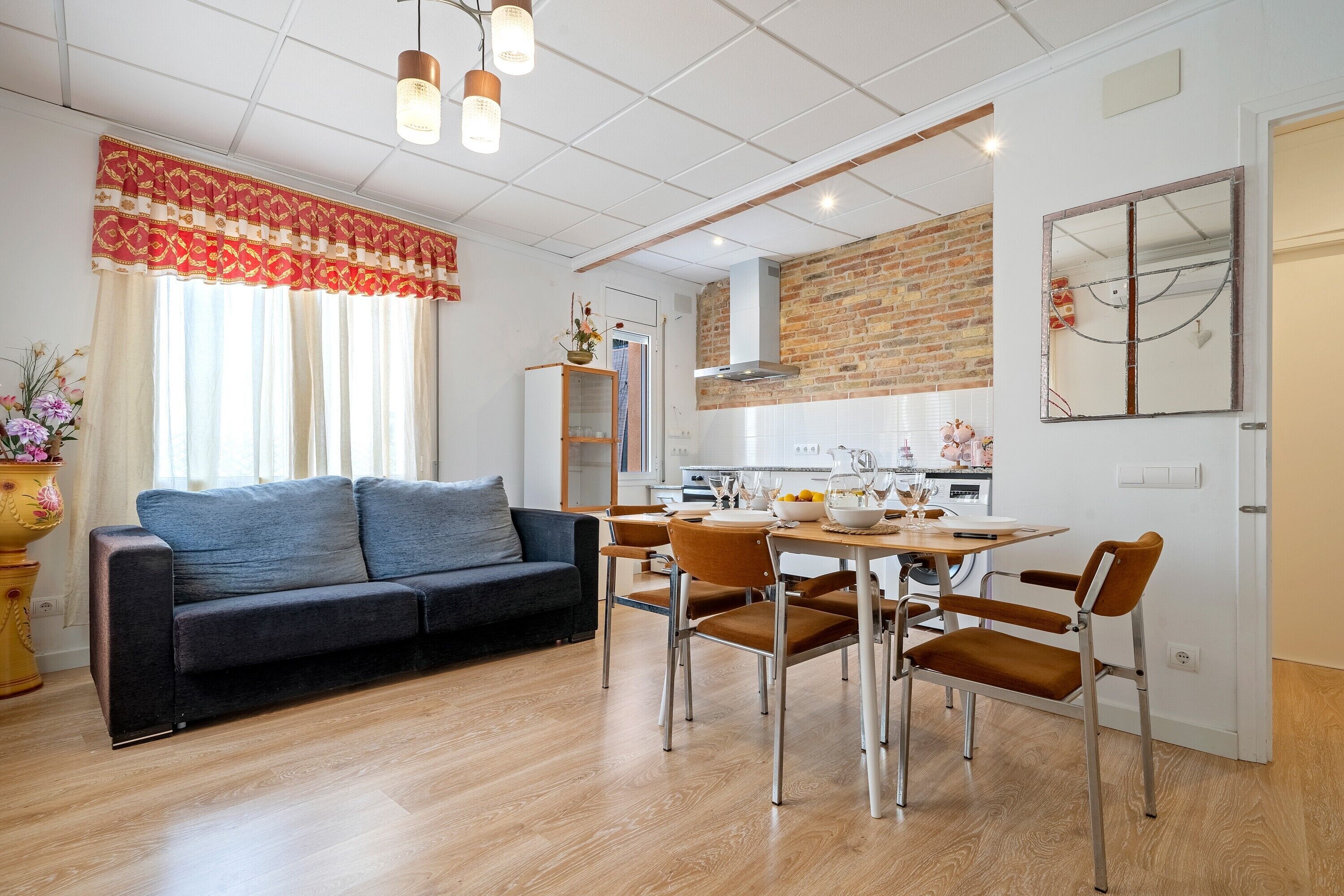 Una sala de estar moderna con un sofá, mesa de comedor, sillas y una cocina al fondo.