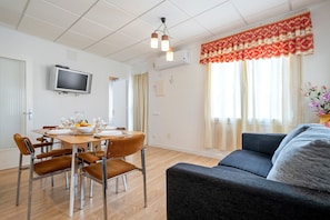 A dining area with a round table, chairs, and a television mounted on the wall.