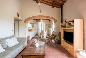 Uma sala de estar com sofá, mesa de centro, televisão e armário de madeira.