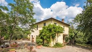 A two-story house with a garden, a patio, and a clear sky. - Holiday Home 'Beretone' with Mountain View, Wi-Fi and Air Conditioning (Radda In Chianti)