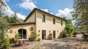 A two-story building with a stone patio, outdoor seating, and potted plants. - Holiday Home 'Beretone' with Mountain View, Wi-Fi and Air Conditioning (Radda In Chianti)