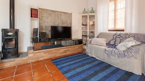 A living room with a fireplace, TV, sofa, and a stone wall.