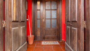 A wooden door with glass panels, a red wall, and a tiled floor.