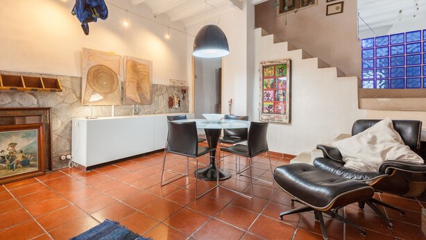A spacious living area with a dining table, chairs, a sofa, and a staircase.