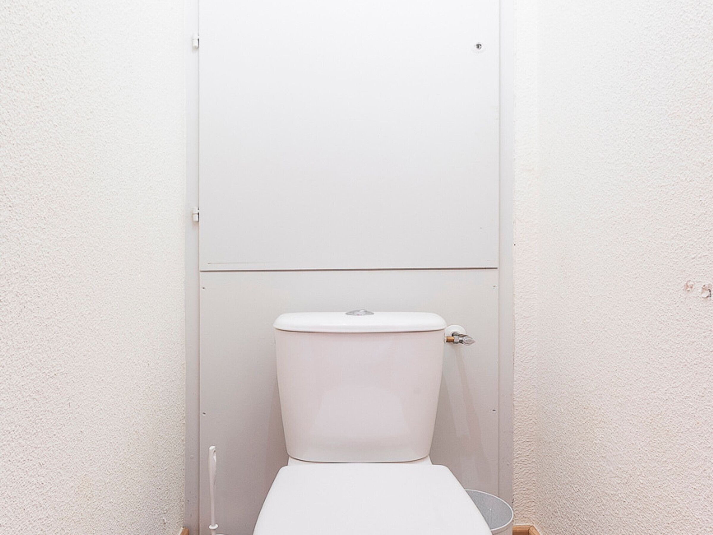 A white toilet in a bathroom with a plain wall and a door.