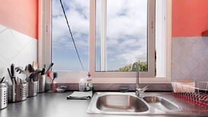 A kitchen with a double sink, a window with a view, and various utensils and appliances.