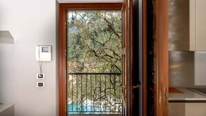 Une pièce avec une porte en bois donnant sur un balcon doté d’une rambarde en métal, un téléphone blanc fixé au mur et une petite fenêtre.