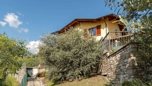 Une maison à deux étages avec un mur en pierre et un balcon.