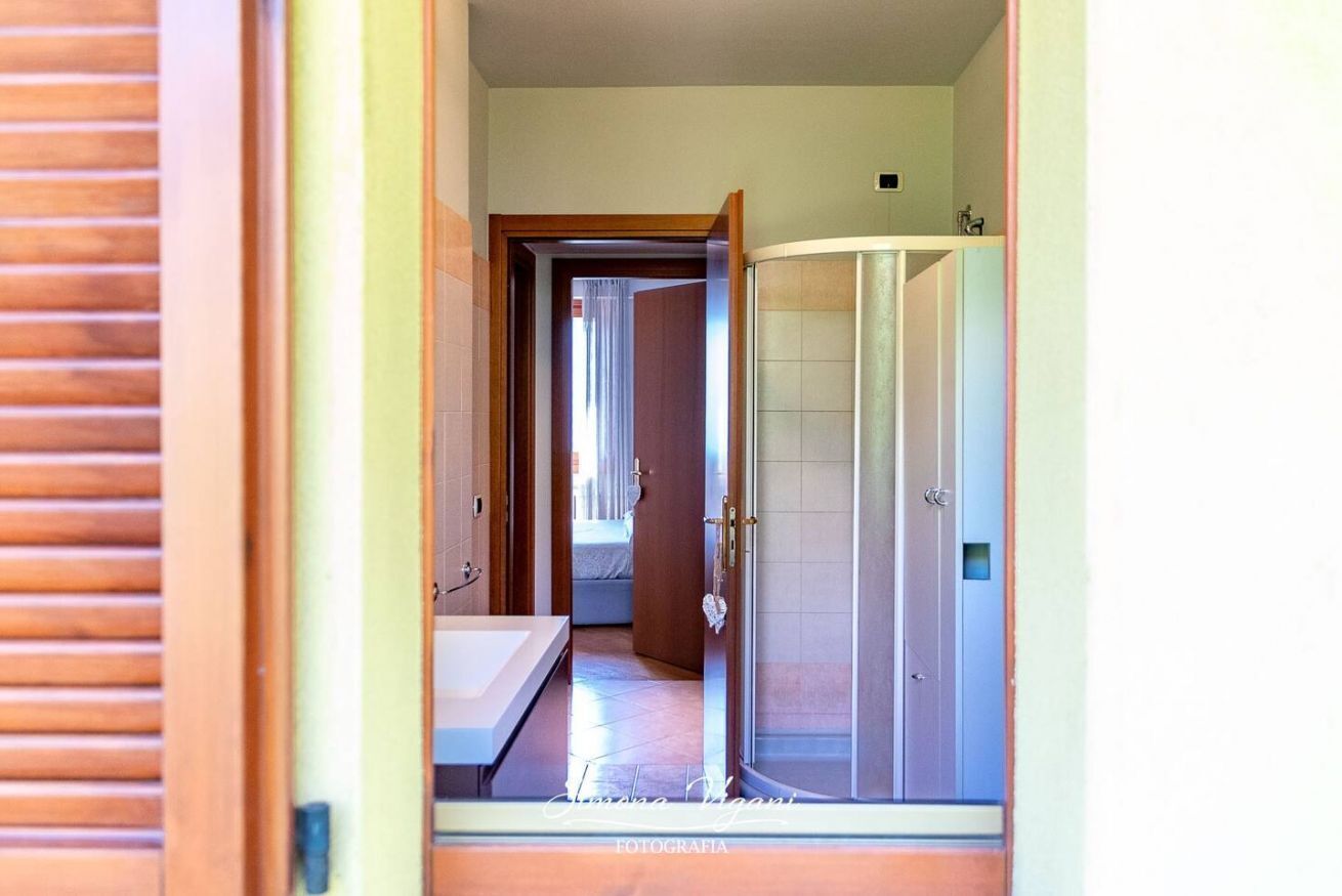 Een gang die leidt naar een badkamer met een douche en een bad.