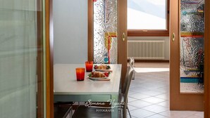 Un coin repas avec une table dressée pour deux personnes, une fenêtre donnant sur le ciel et un radiateur en arrière-plan.
