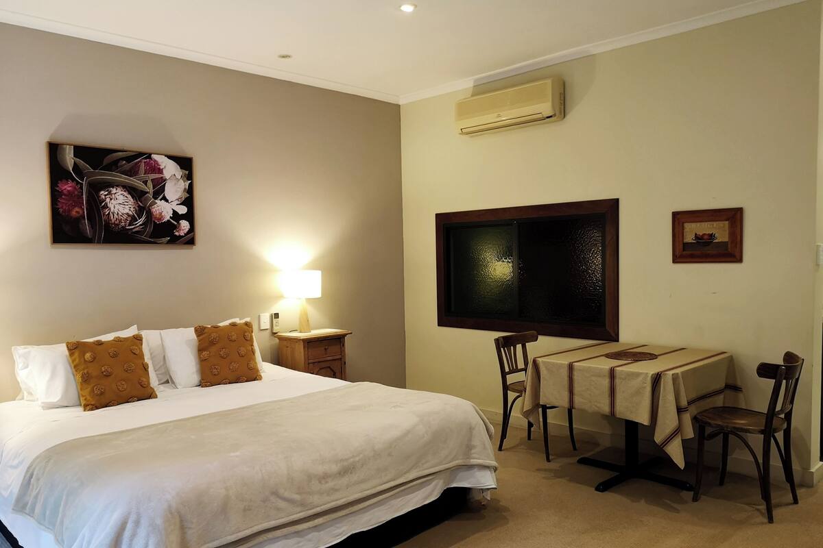 Een hotelkamer met een groot bed, een bureau met stoel, een televisie en een schilderij aan de muur.