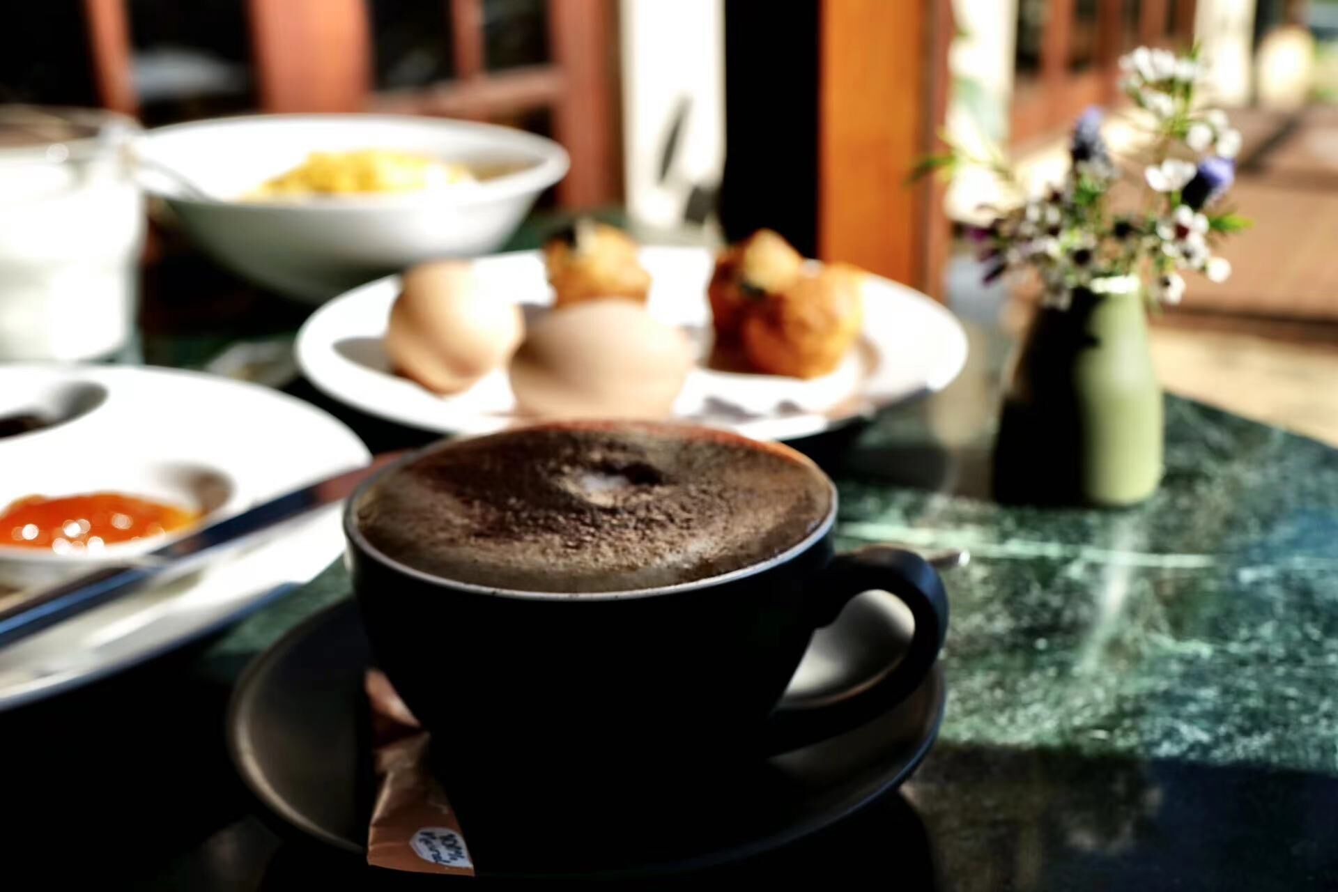 Una taza de café sobre un plato, con un fondo desenfocado de una mesa de comedor.