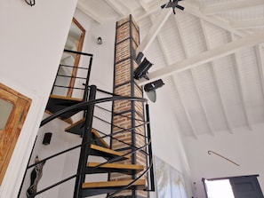 Una escalera de caracol con un pilar de ladrillo, una puerta de madera y un mapa en la pared.
