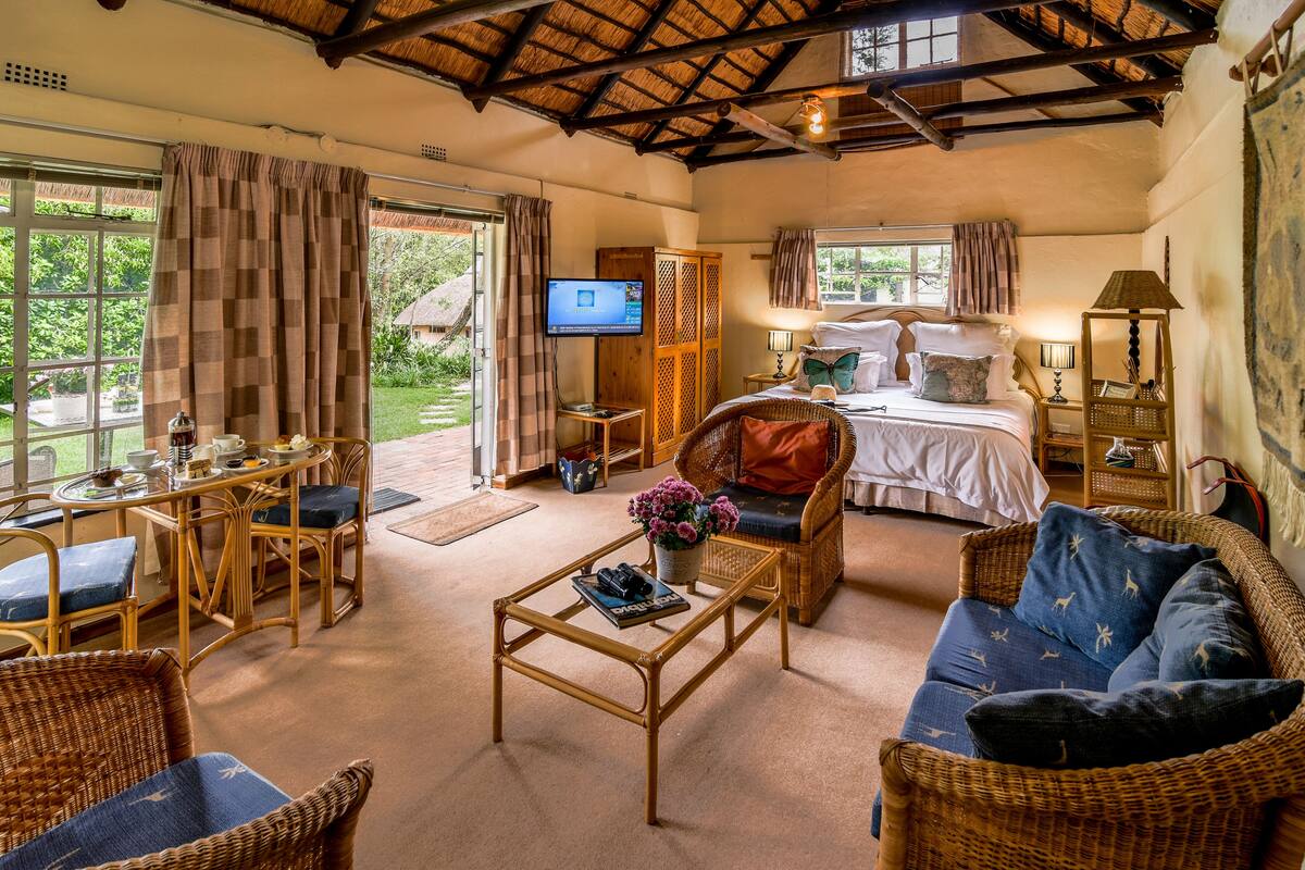 A spacious room with a bed, a television, a dining area, and a seating area with a coffee table and chairs.