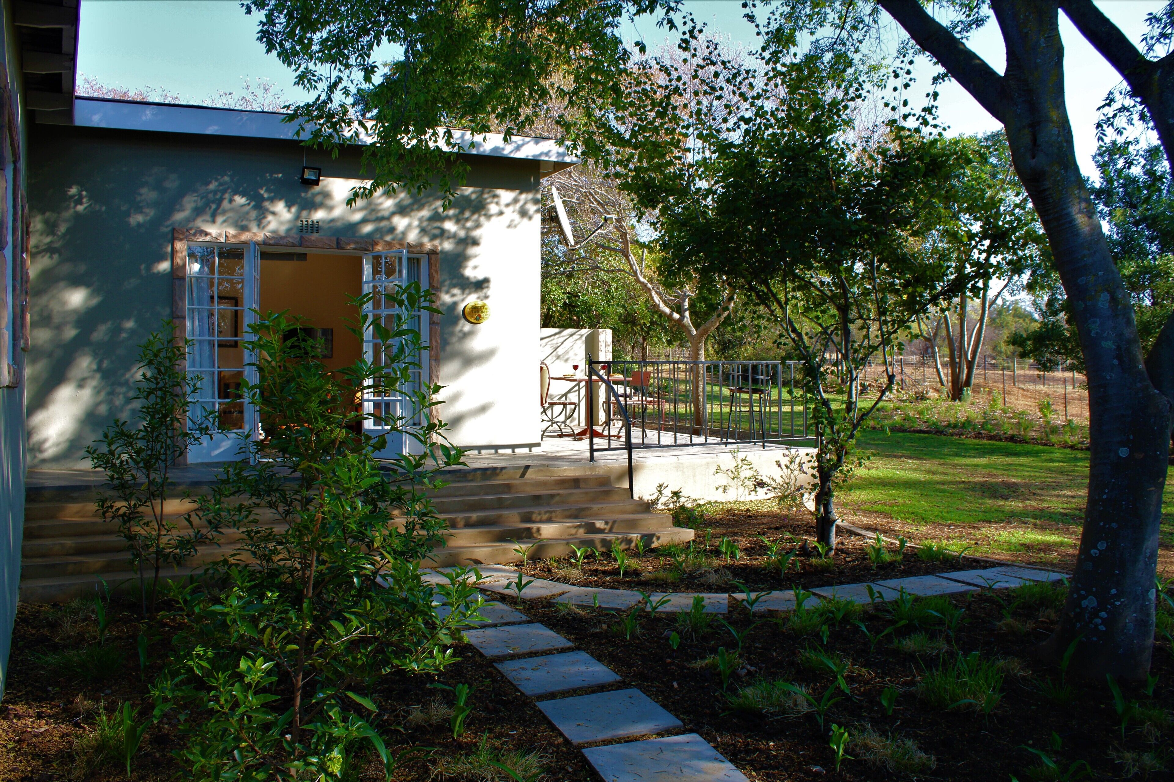 A house with a front porch, steps leading to the entrance, and a small garden area with a tree and plants.