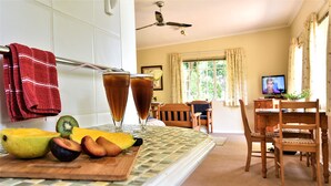A kitchen with a dining area, a ceiling fan, and a television.