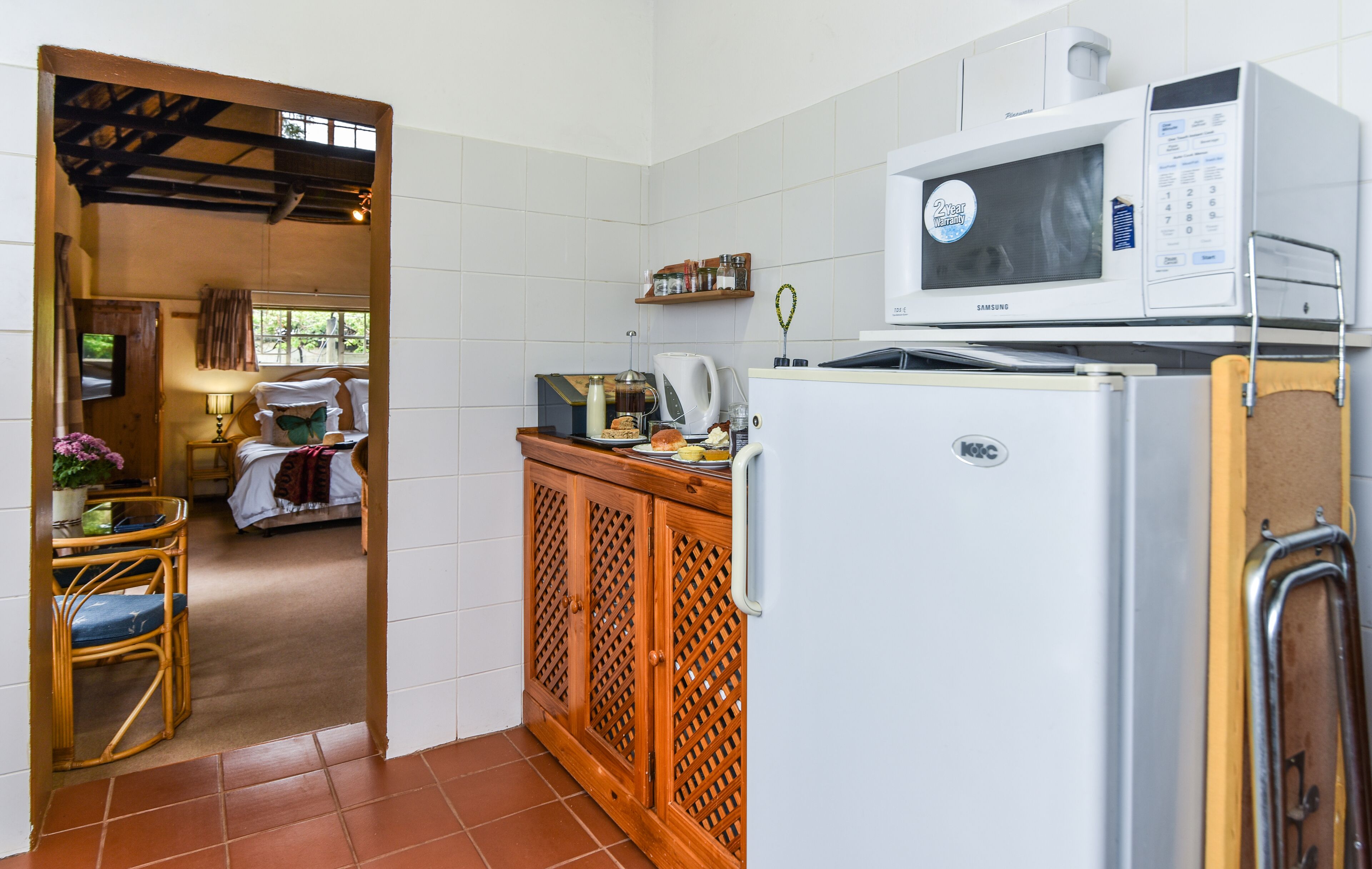 A compact kitchen with a microwave, refrigerator, and wooden cabinets.