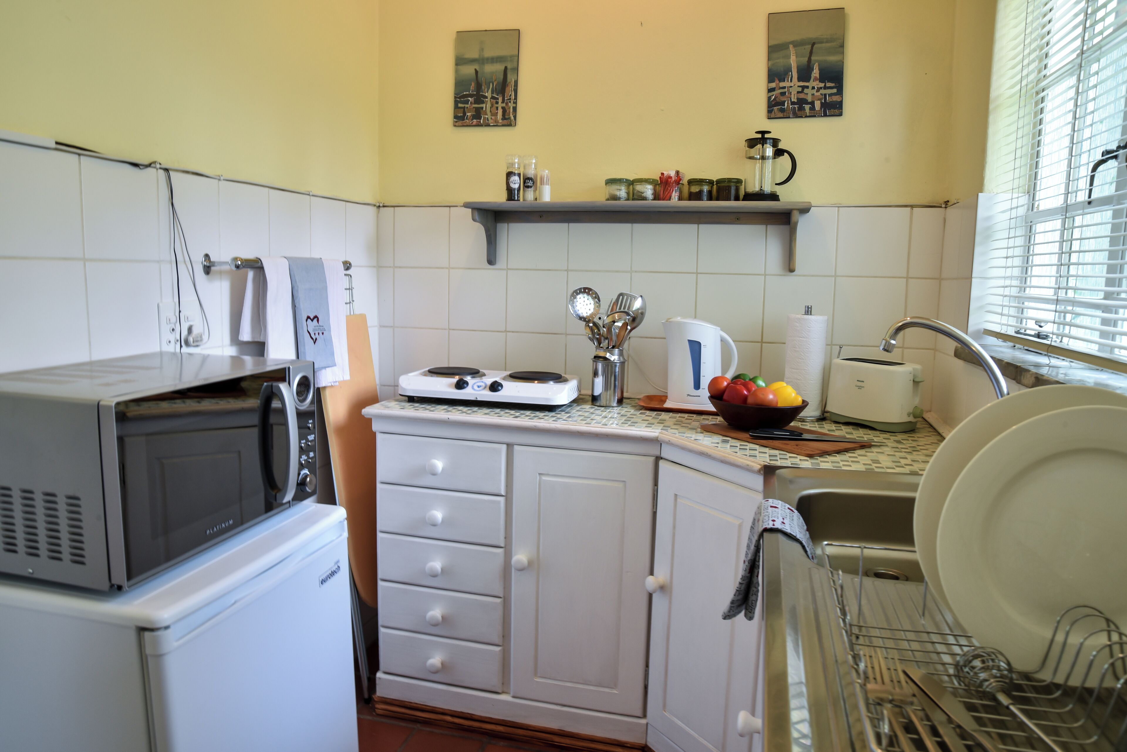 A compact kitchen with a microwave, toaster, and sink.