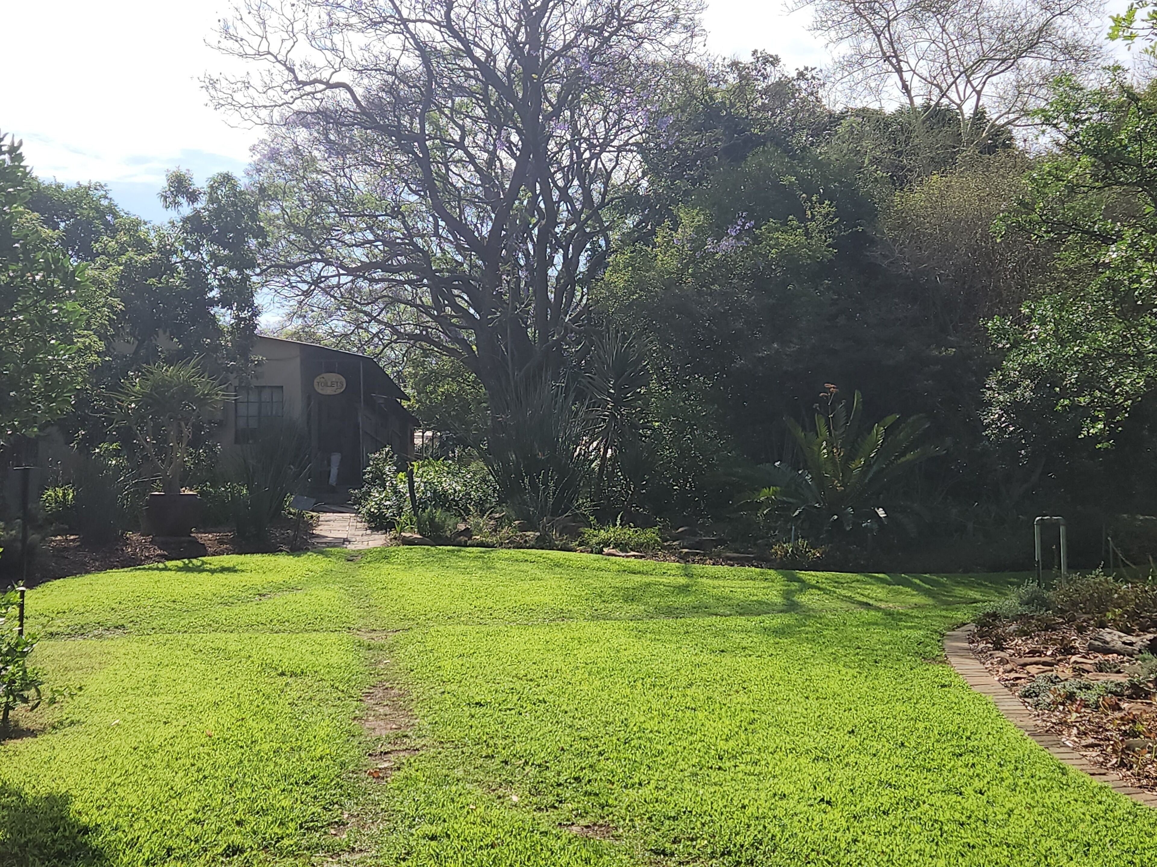 A well-maintained grassy area with a pathway leading to a building marked 'TOILETS'.