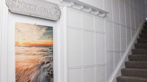 A staircase with a 'Be our guest' sign above it, leading to a room with a large ocean sunset painting. - 2 Seaview @ Bridlington Bay (Bridlington)