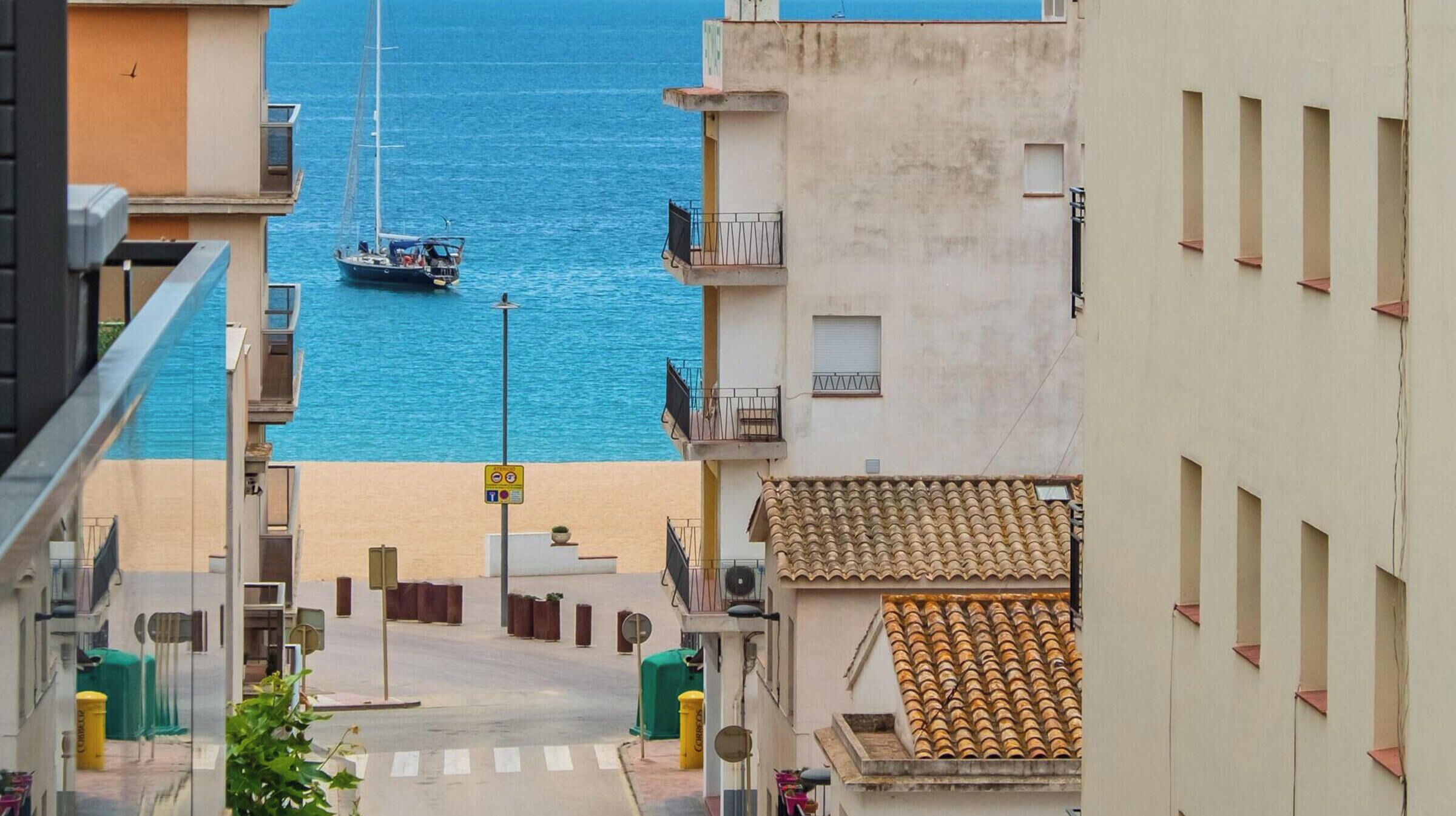 Una calle estrecha flanqueada por edificios, con un bote en el agua al fondo y un paso de peatones.