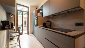 A modern kitchen with a built-in stove, a coffee machine, and a large window overlooking a garden.