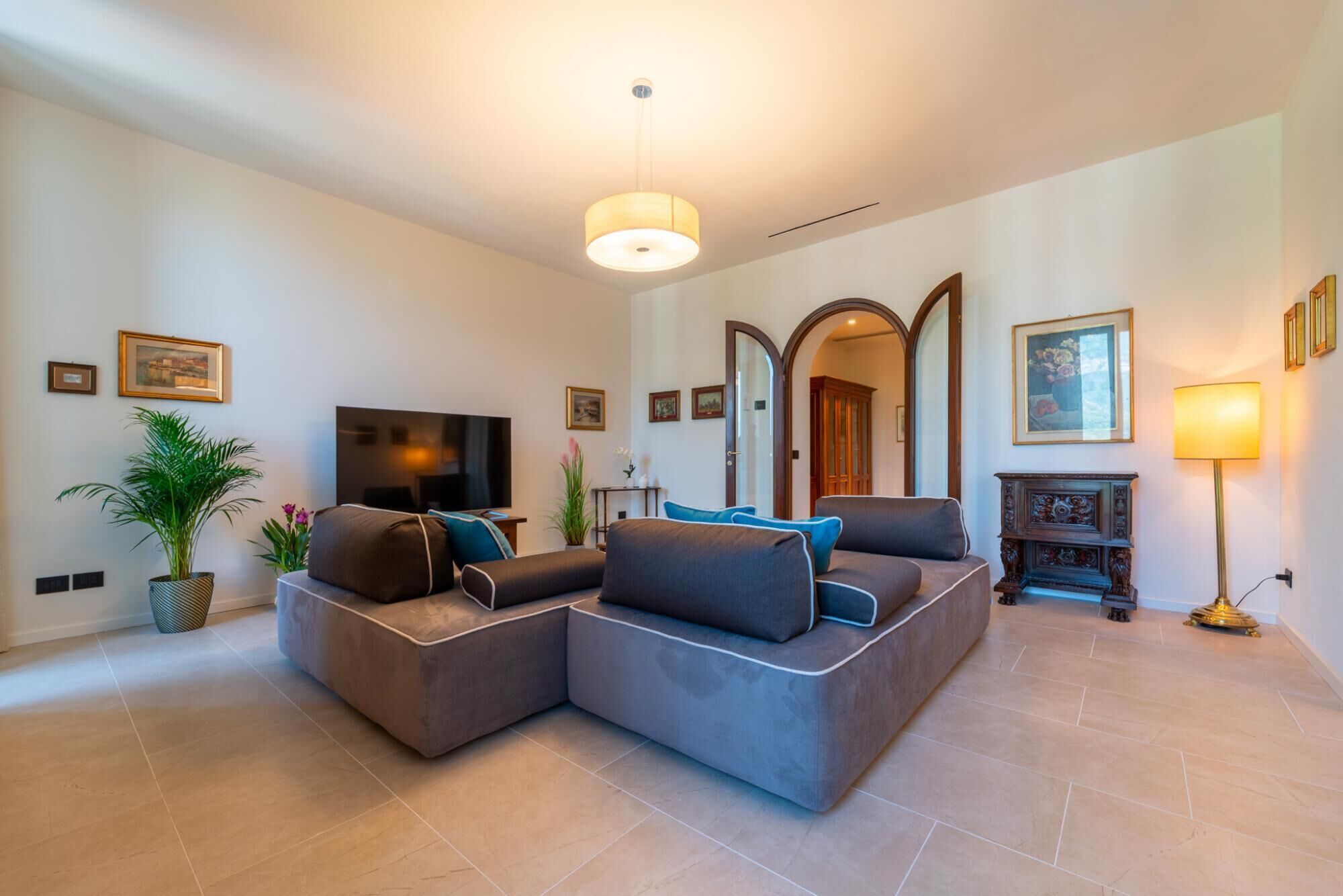 A modern living room with a sectional sofa, a flat-screen TV, a fireplace, and a large mirror.