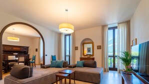 A modern living room with a sofa, coffee table, and TV. There is a dining area visible through an archway. - Eleganza e Stile nel Cuore di Bellagio by Wonderful Italy (Bellagio)