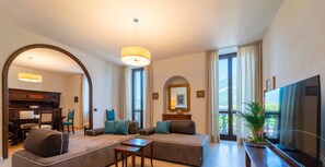 A modern living room with a sofa, coffee table, and TV. There is a dining area visible through an archway. - Eleganza e Stile nel Cuore di Bellagio by Wonderful Italy (Bellagio)
