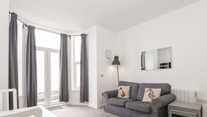 A modern living room with a grey sofa, white chair, and a small table.