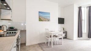 A modern kitchen with a stove, sink, and a dining area with a table and chairs.