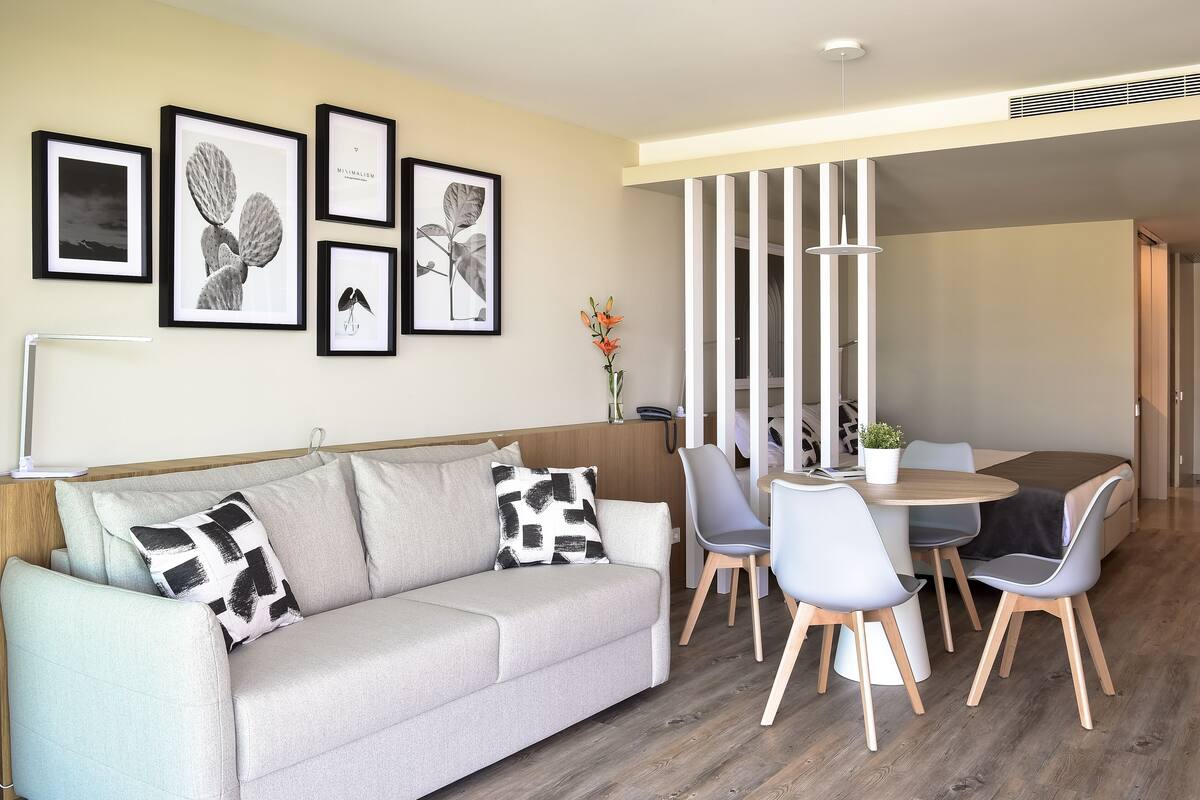 Ein modernes Wohnzimmer mit einer Couch, einem Esstisch mit Stühlen und gerahmten Kunstwerken an der Wand.