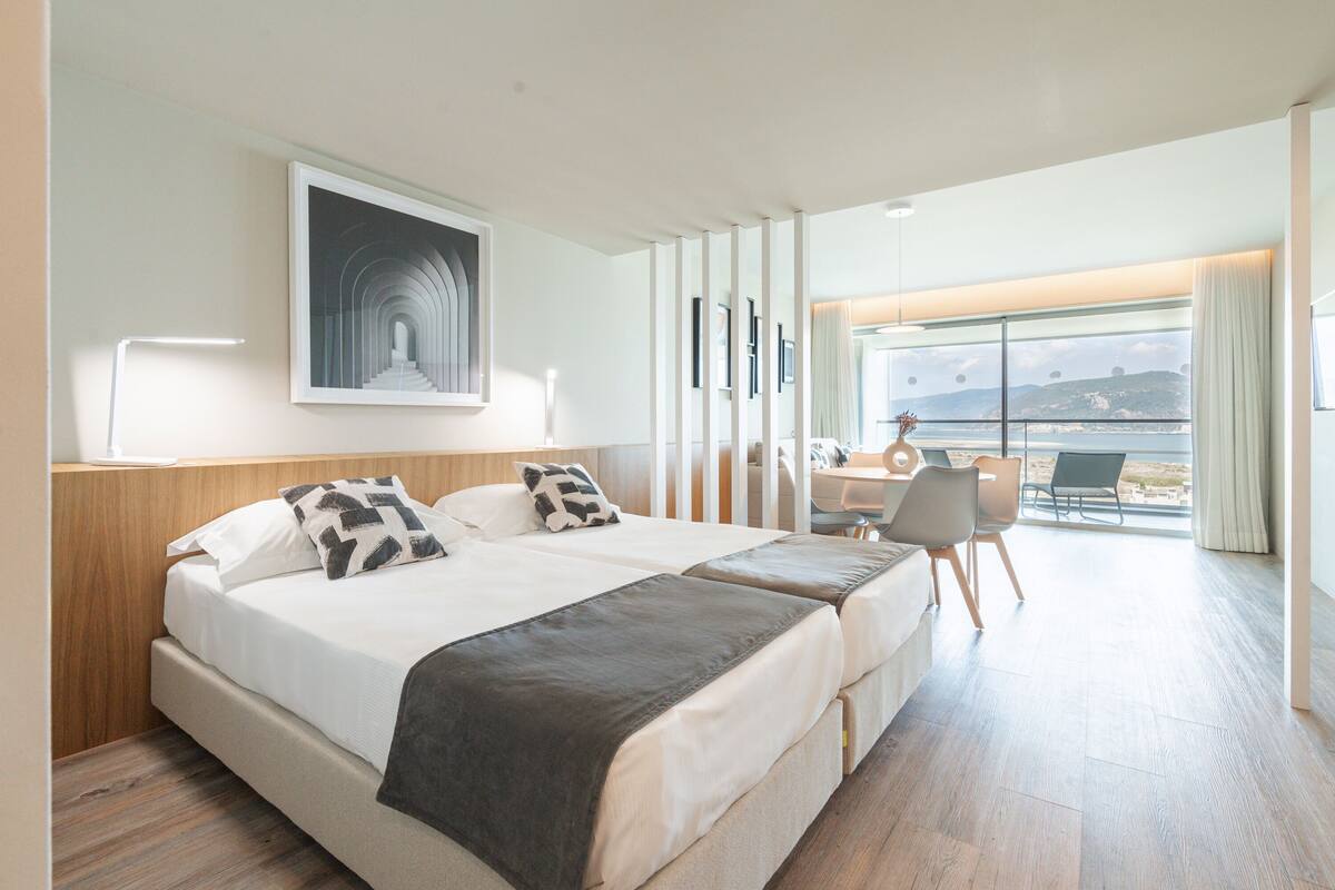 Ein modernes Hotelzimmer mit einem großen Bett, einem Schreibtisch und Blick ins Freie.