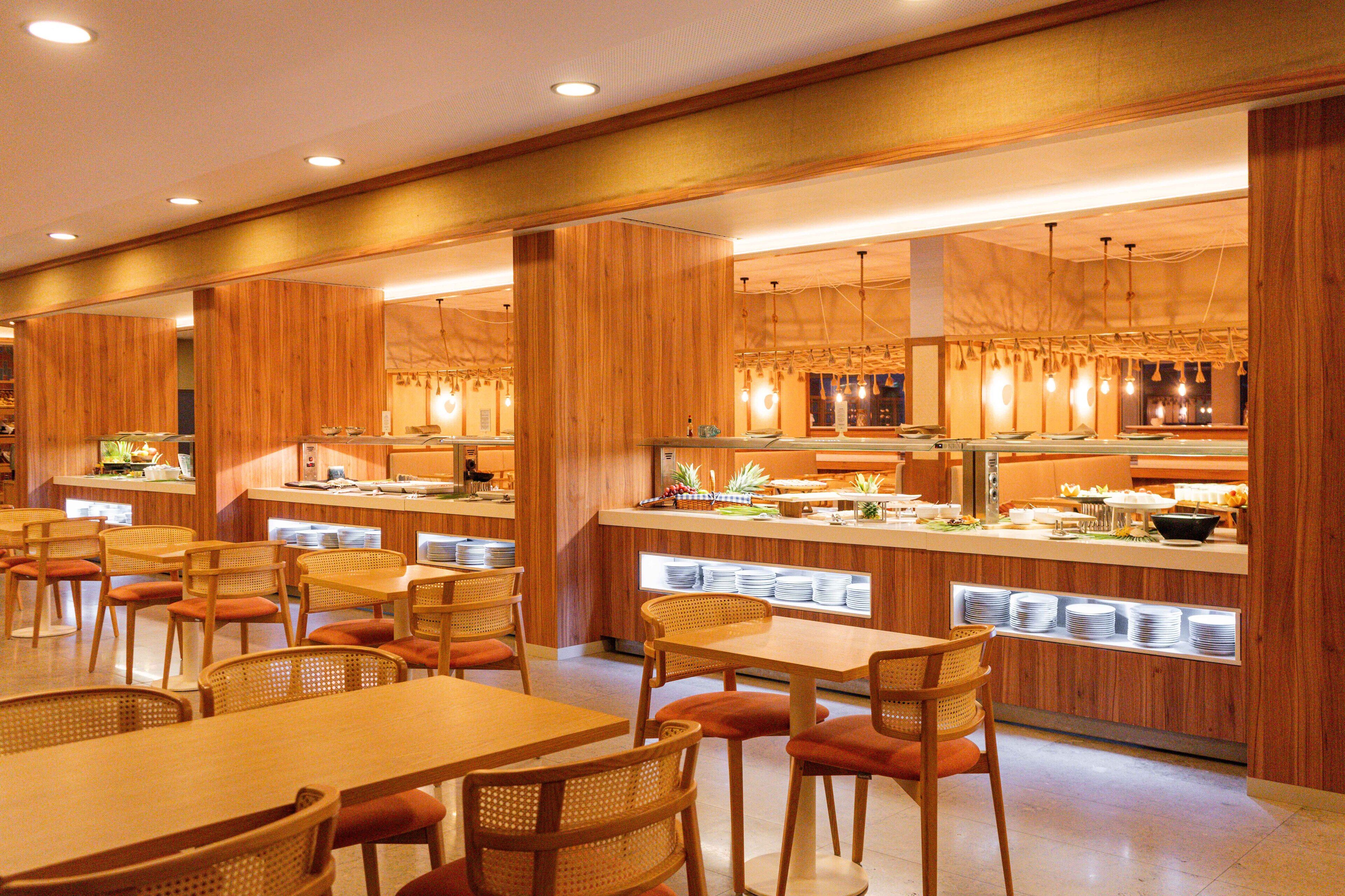 Un restaurante con paneles de madera, mesas, sillas y una zona de bufé.