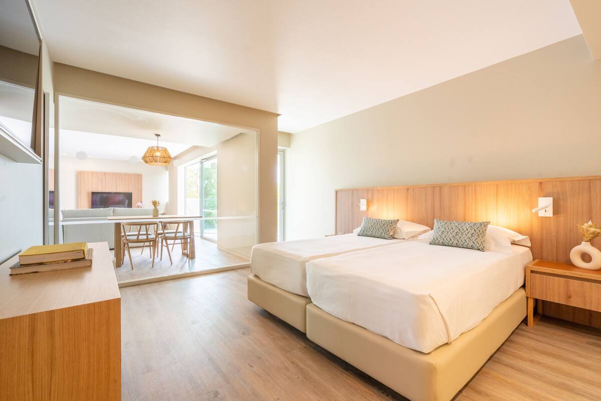 Ein modernes Schlafzimmer mit einem großen Bett, Nachttischen, einem Schreibtisch und einer Essecke.