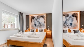 Un dormitorio moderno con una cama grande, cabecera de madera y un cuadro de un carnero.