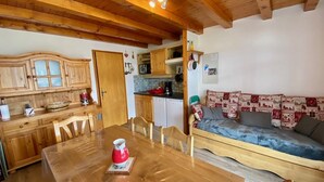 Een gezellige keuken met houten kastjes, een eettafel met stoelen en een bank met gestreepte kussens.