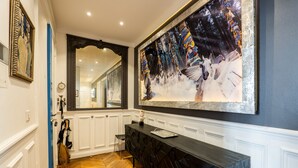 A hallway with a wooden herringbone floor, a black console table, and a large abstract painting on the wall. - Timeless Majesty, by Veeve (Paris)