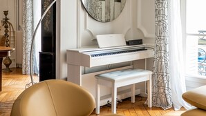 A room with a piano, a round mirror, and a modern chair. - Timeless Majesty, by Veeve (Paris)