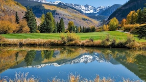A serene lake with a clear reflection, surrounded by autumn foliage and mountains in the background. - Lionshead Village - Montaneros 1 Bedroom (Vail)